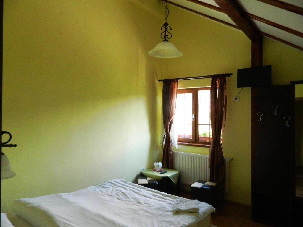 a bedroom with a bed and a window at Hanul cu Noroc in Moieciu de Jos