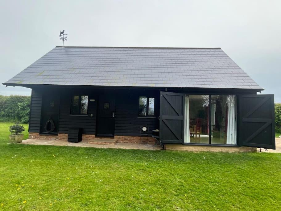 uma casa preta com um telhado preto num campo verde em Family friendly rural idyll with space for tents em Wittersham