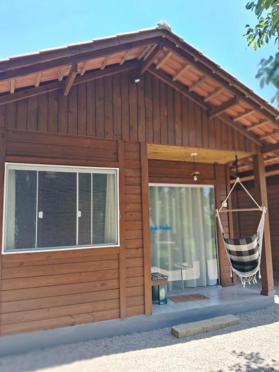 a small house with a porch with a net at Chalés Lar Doce Mar Camacho SC in Jaguaruna