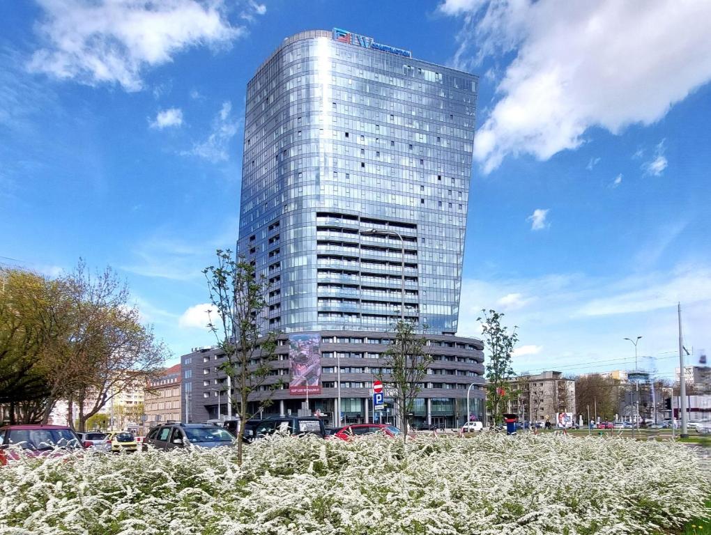 un edificio de cristal alto frente a un aparcamiento en Hanza Tower STETT-INN Business & Holiday en Szczecin