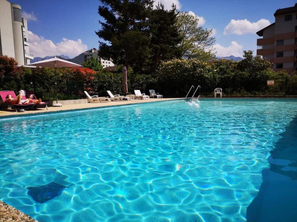 a large swimming pool with blue water in a resort at Mont Royal balcon et piscine in Annecy