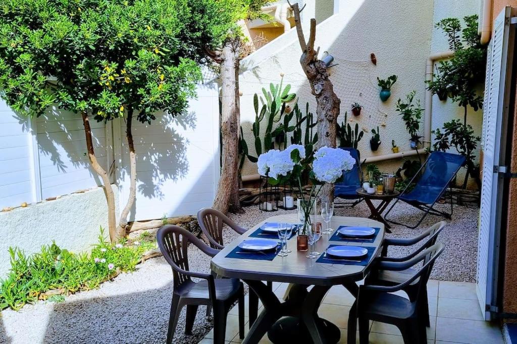 Una mesa y sillas en un patio. en Le MARINE Rez de Jardin direct Plage Parking Privé Climatisé, en Sète