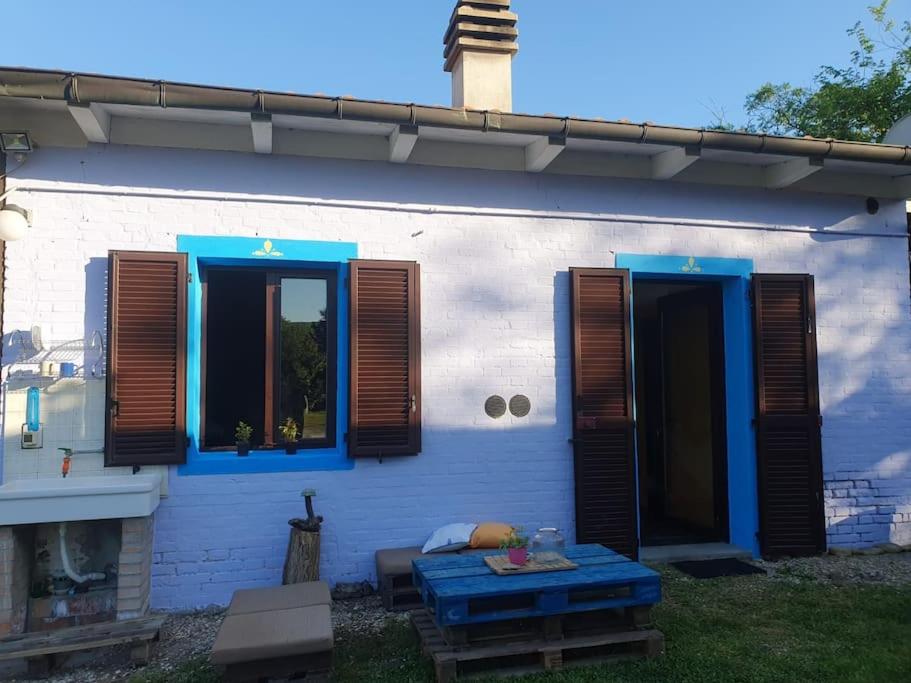 uma casa com persianas azuis e uma mesa em frente em Loft immerso nel bosco em Rivola
