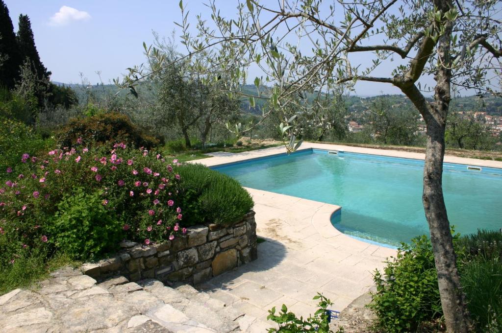 una piscina in un giardino con albero e fiori di I Parigi Corbinelli Residenze a Firenze