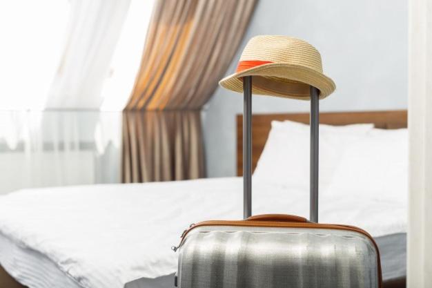 um chapéu sentado em cima de uma mala numa cama em Camere Masaccio em Certaldo