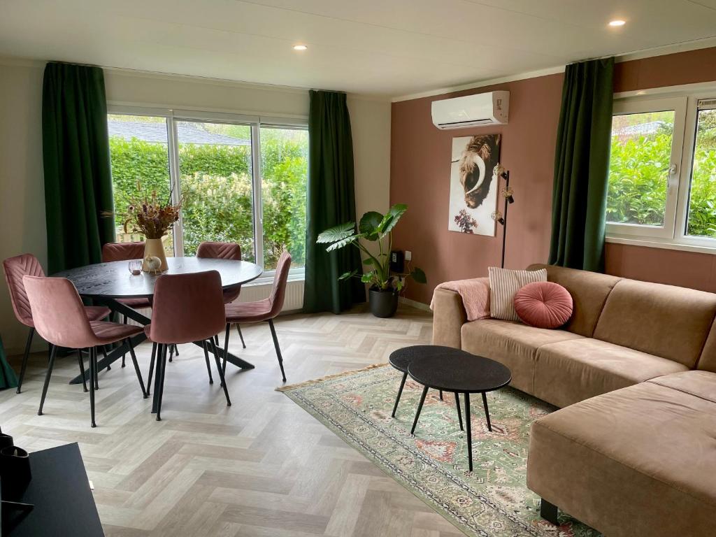 a living room with a couch and a table and chairs at Chalet vakantiepark Beekbergen in Beekbergen