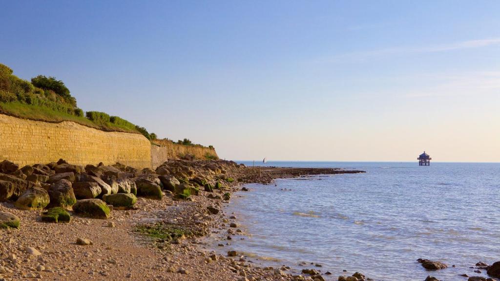 a beach with rocks and the ocean with a horse in the distance at Nuit insolite dans un petit voilier in La Rochelle