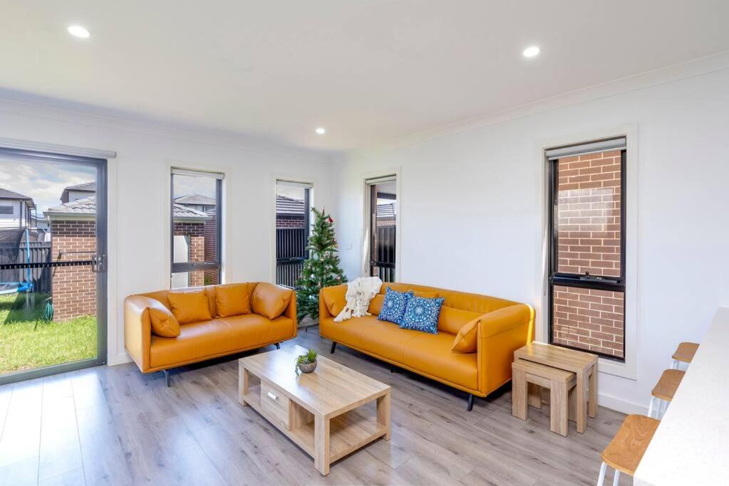 a living room with two orange couches and a table at Lovely 4 bedrooms house to Ed station in Ingleburn