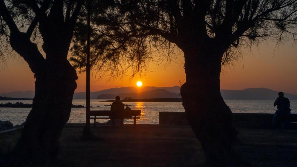 a person sitting on a bench watching the sunset at MARTAS HOUSE in Daratso