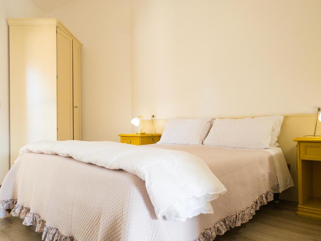 a white bedroom with a bed with white sheets and pillows at Hotel Donatella in Posada