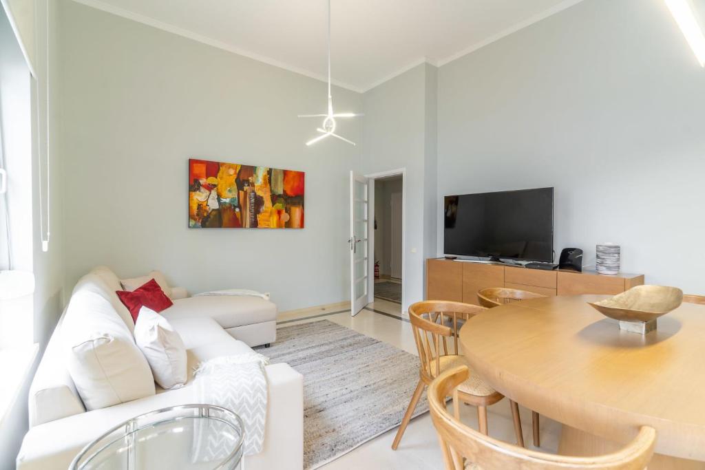 a living room with a white couch and a table at Apart T3 com piscina tenis ginasio e parq infant in Lisbon