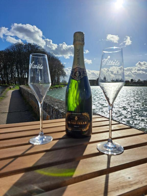 a bottle of wine and two glasses on a table at BATEAU - CANAL DU NIVERNAIS NIEVRE in Bazolles