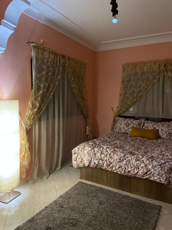 a bedroom with a bed with curtains and a lamp at Riad malak in Marrakesh
