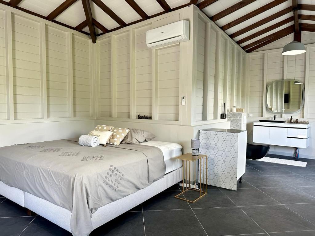 - une chambre avec un lit et une salle de bains pourvue d'un lavabo dans l'établissement Cosy bungalow au Diamant, au Diamant