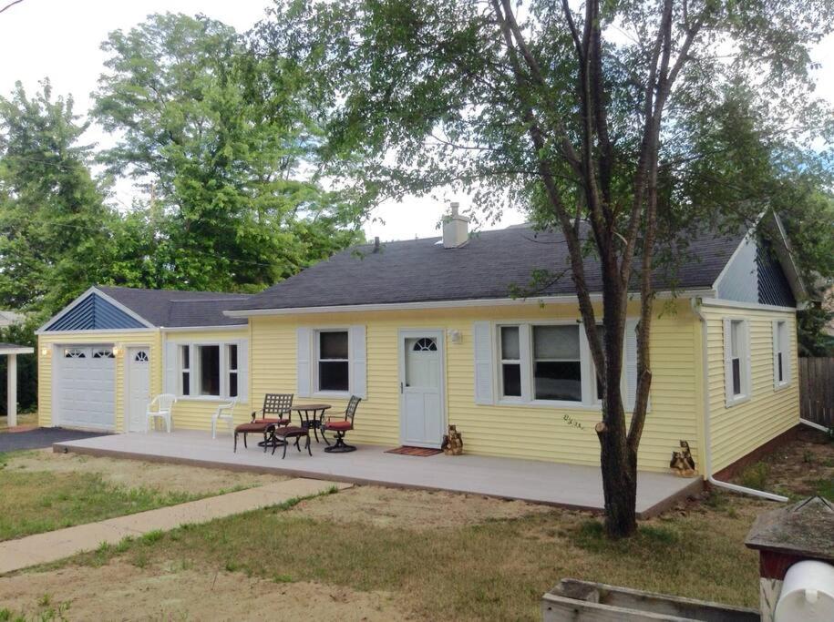 ein gelbes Haus mit einem Picknicktisch davor in der Unterkunft Cozy Quiet Gem Near Sheridan Beach in Michigan City