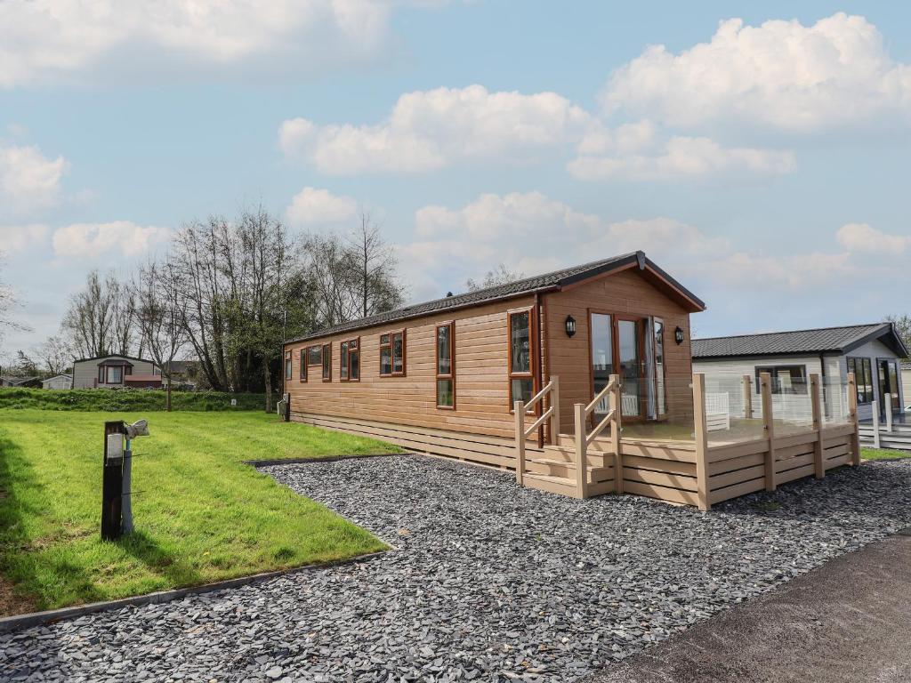 a small wooden cabin with a gravel driveway at Lodge 1 in St Asaph