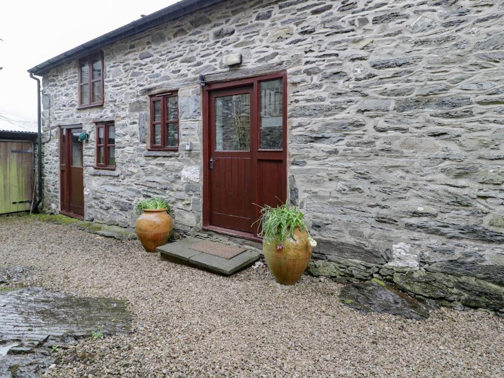 um edifício de pedra com dois vasos na frente de uma porta em Graig Las The Barn em Oswestry