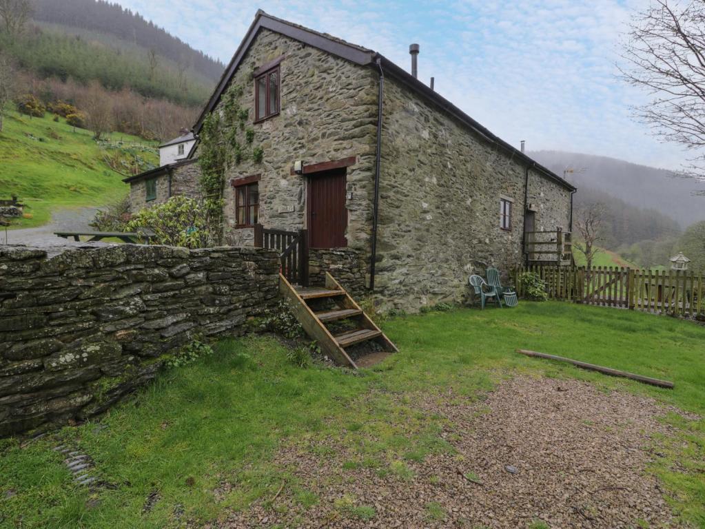 an old stone house with a stone wall at Graig Las The Stables in Oswestry