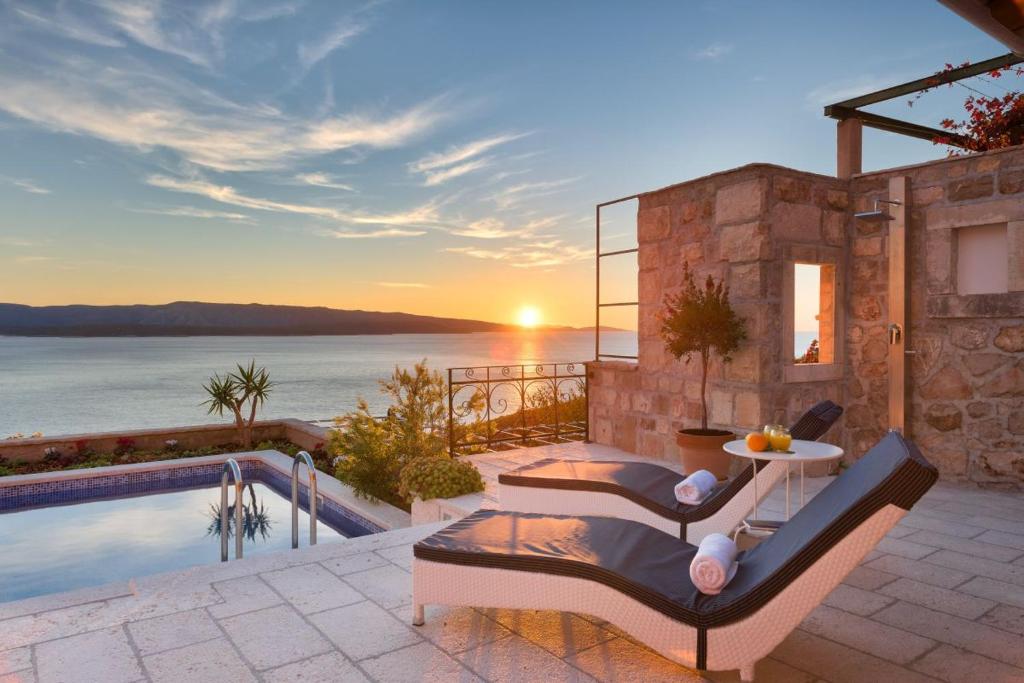 a villa with a swimming pool and a sunset at Luxury Villa Murvica with private pool near the beach in Murvica on Brac island in Murvica