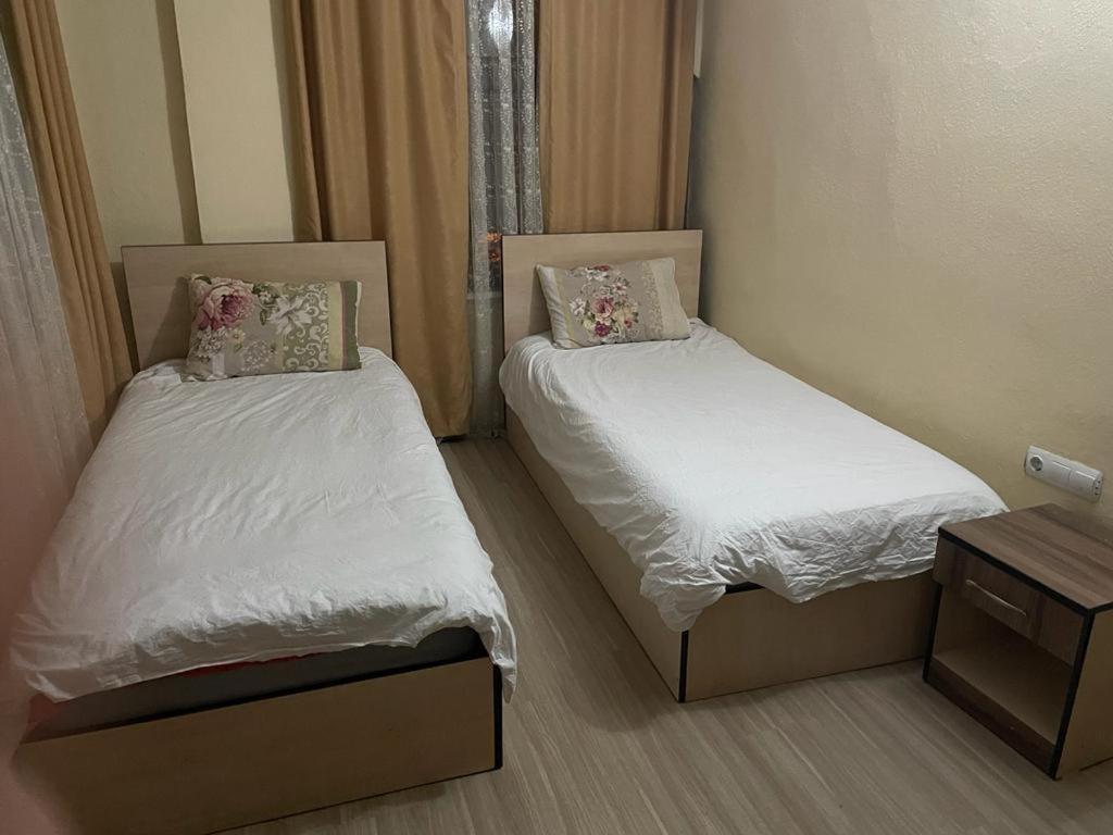 two beds in a room with white sheets and pillows at Apaydın otel in Büyükçakır