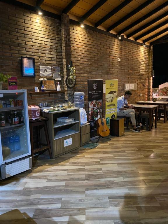 mężczyzna siedzący przy stole z gitarą w sklepie w obiekcie Bali Caps Hostel by Xhosteller w mieście Kuta