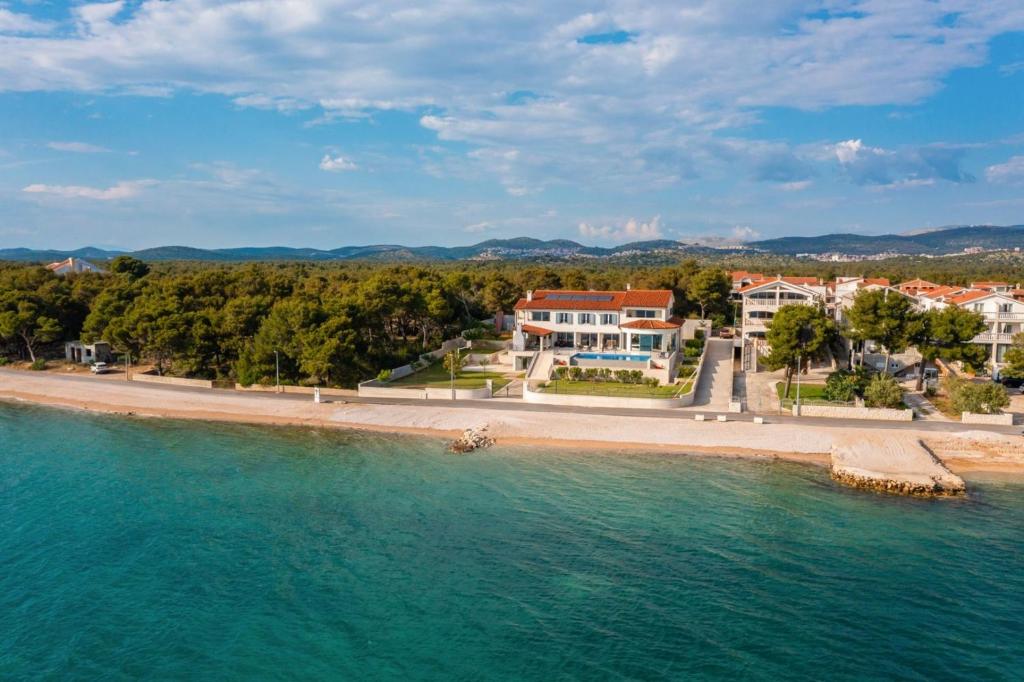 una vista aérea de una playa con casas y agua en Luxury Villa Sea Whisper with private pool, sauna, jacuzzi and gym by the sea - Šibenik, en Šibenik