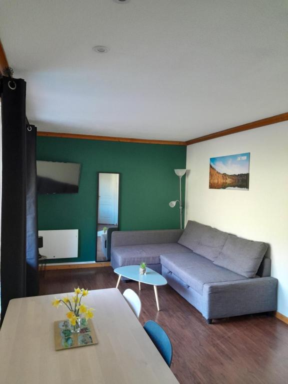 een woonkamer met een bank en een tafel bij T2 confortable - Piscine chauffée - Super Besse in Besse-et-Saint-Anastaise