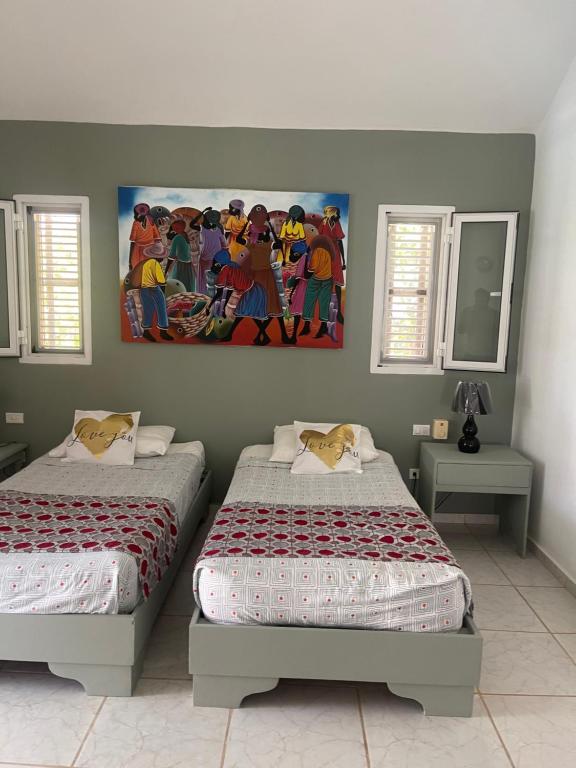 two beds in a room with a painting on the wall at Villa Del Mar in Las Terrenas