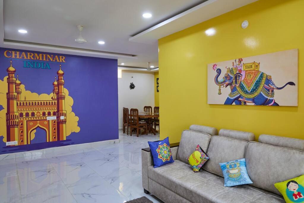 a living room with a couch and a wall with a mural at Cozy 3 bhk A/C home @ wipro circle , Near US Embassy in Hyderabad