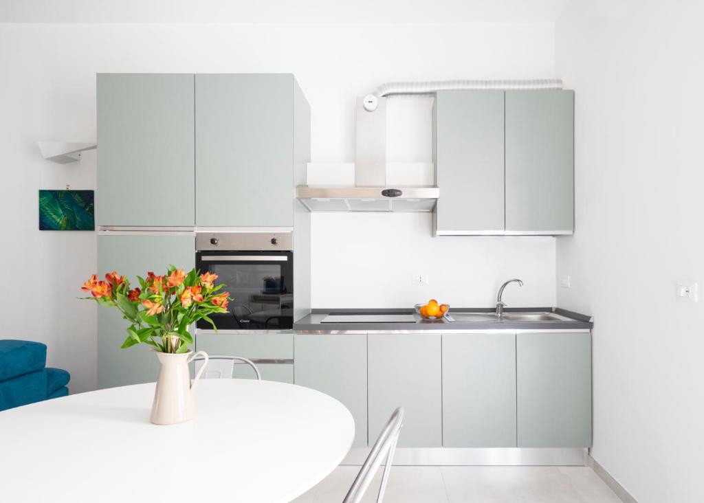 a white kitchen with a table and a vase of flowers at @uRhOME - Luxury Accommodation in Rome