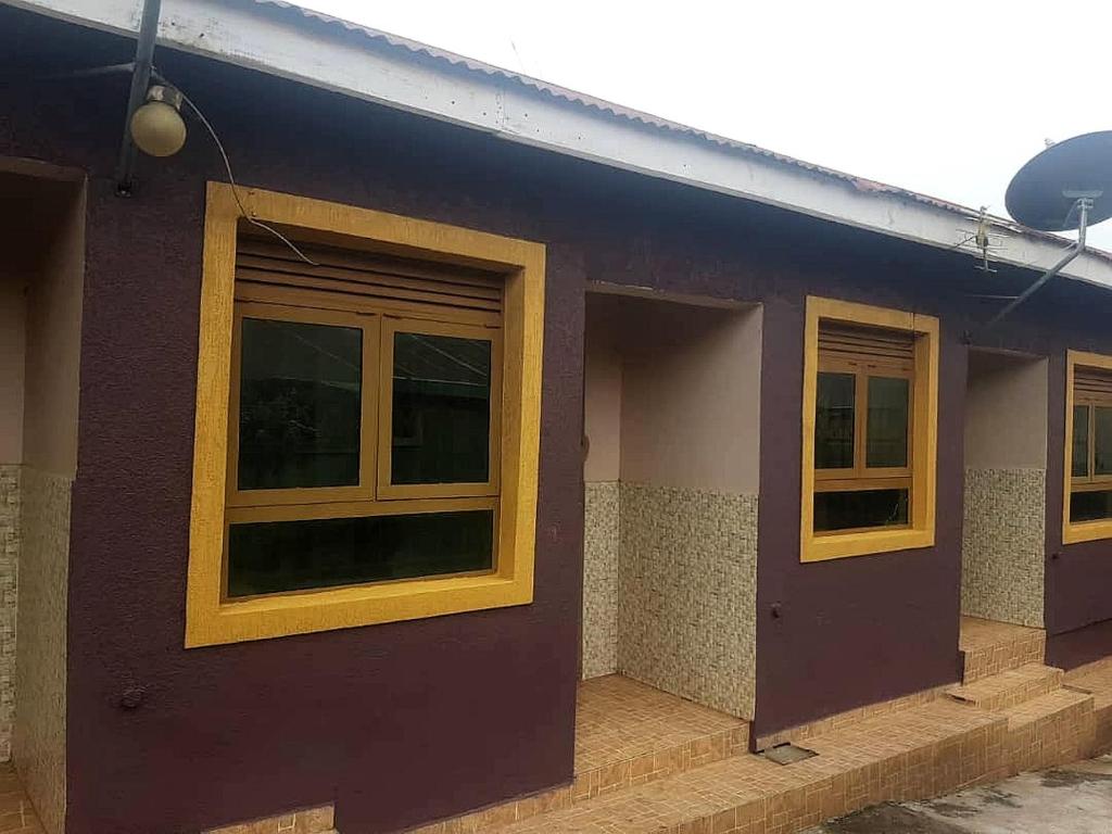 una casa morada con ventanas amarillas. en Petite paradise, en Kampala
