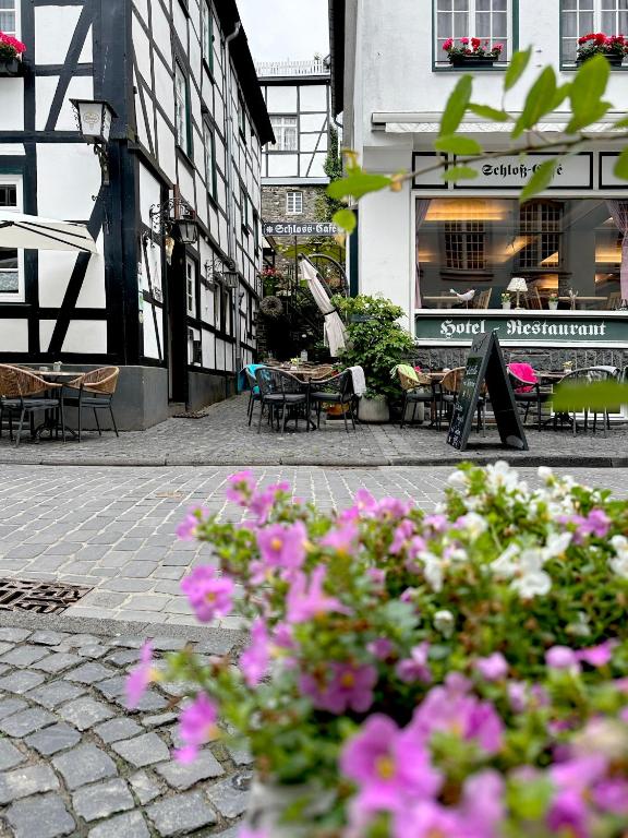 a courtyard with tables and chairs and pink flowers at Hotel Royal in Monschau