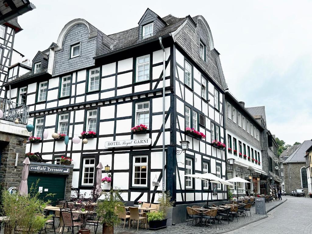 un grand bâtiment noir et blanc avec des tables et des chaises dans l'établissement Hotel Royal, à Monschau