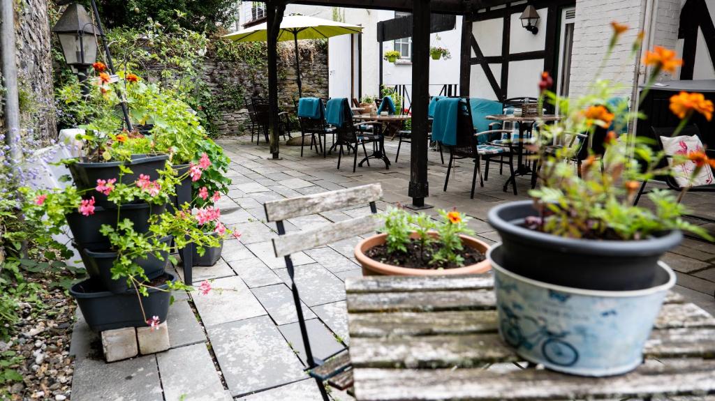 a patio with pots of flowers and tables and chairs at Hotel Royal in Monschau