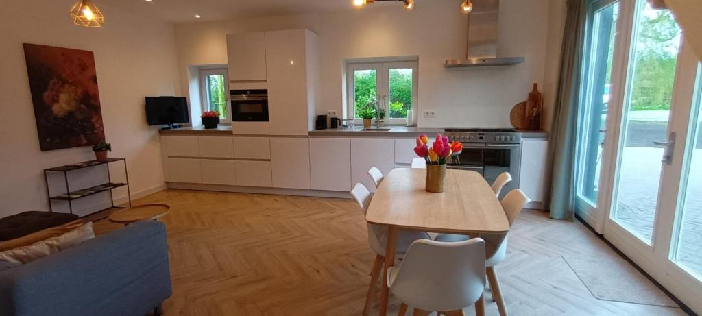 cocina y sala de estar con mesa y sillas en Ons Huisje Achter, en Noordwijkerhout