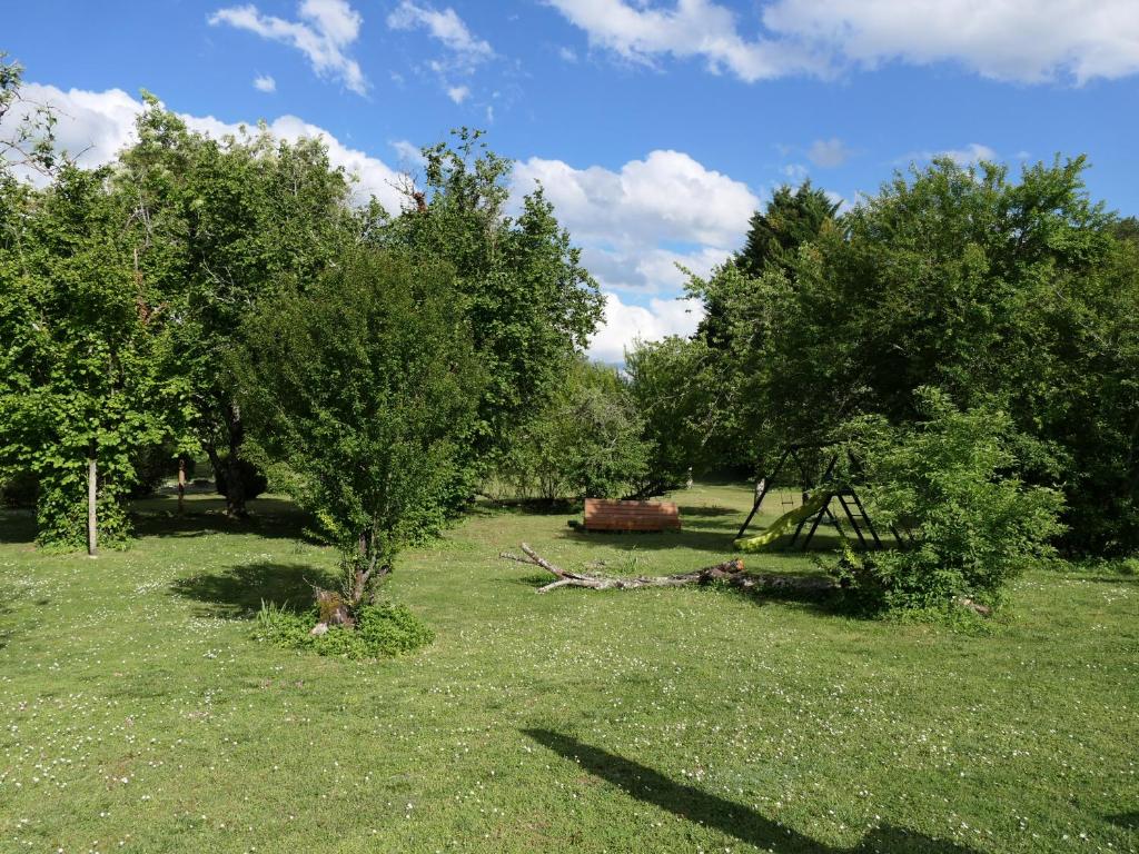 a field with trees and a bench in the grass at Le Moulin du Clapier La Banette in Sorges