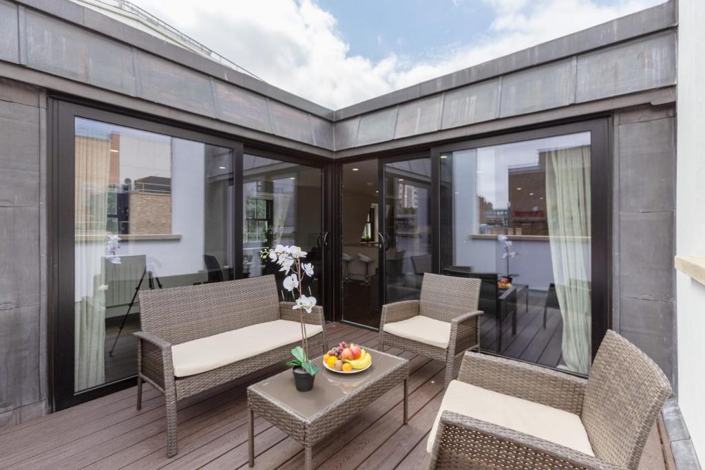 a balcony with chairs and a table with a bowl of fruit at Penthouse with Private Terrace Soho - CityApartmentStay in London