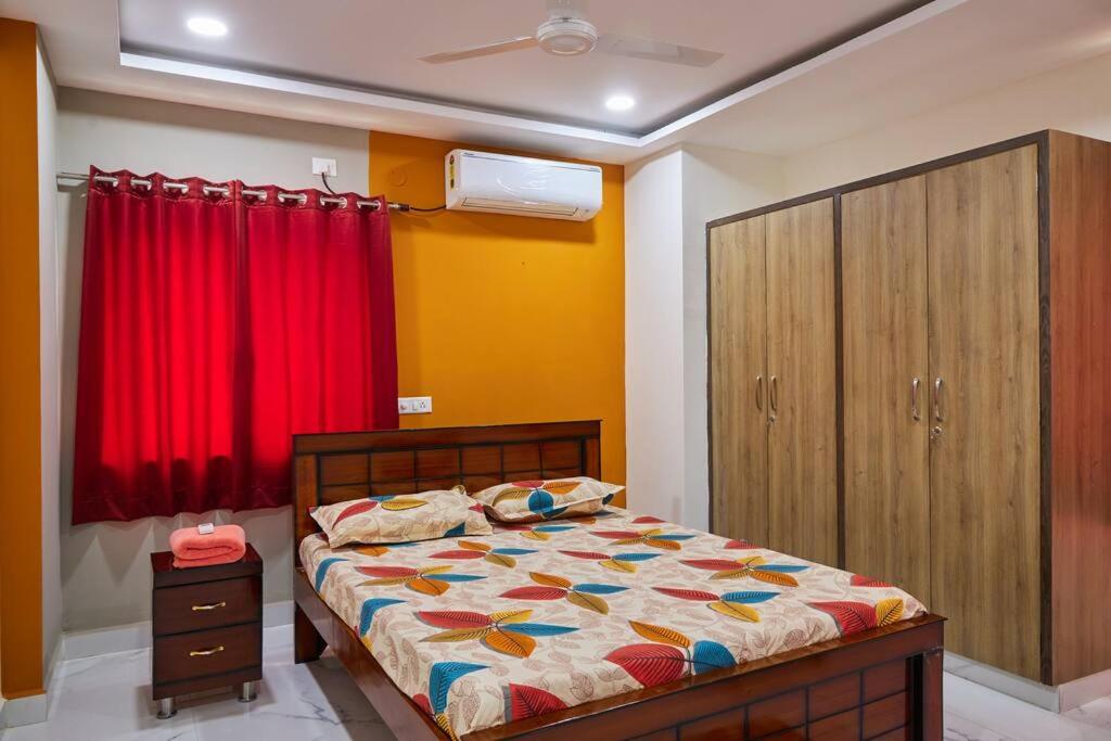 1 dormitorio con cama y cortina roja en Pent House 1BHk @WiproCircle, Near US Embassy, Gachibowli en Hyderabad