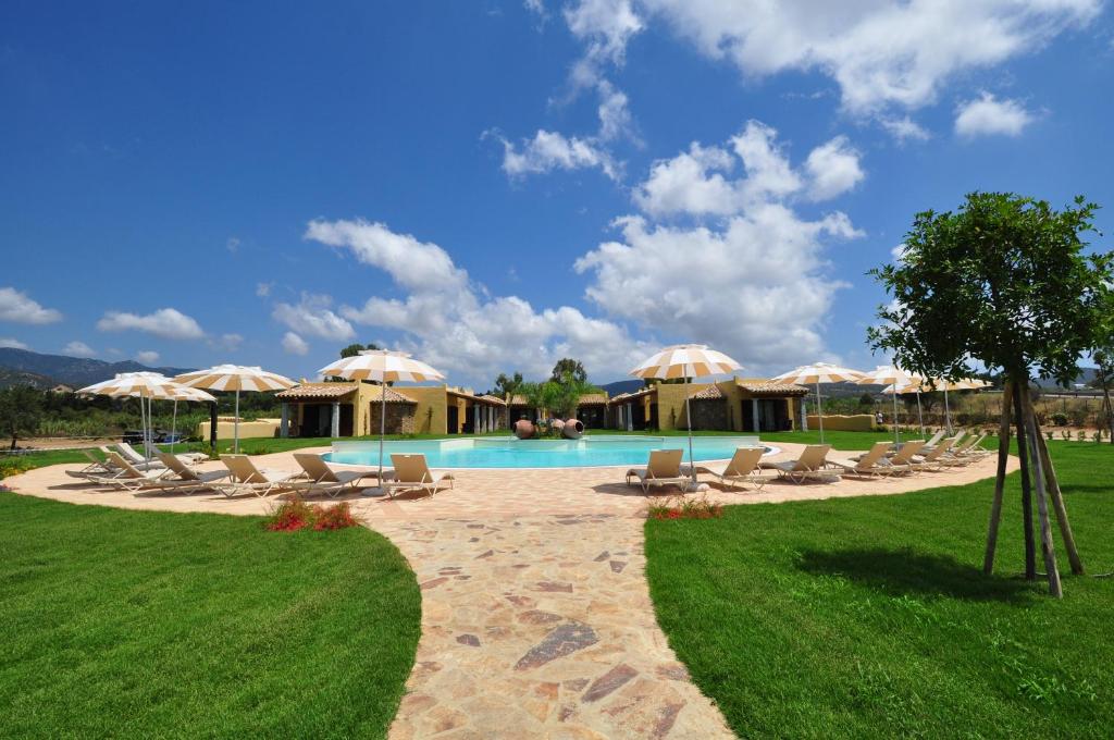 een zwembad met ligstoelen en parasols bij Le Anfore Hotel in Villasimius