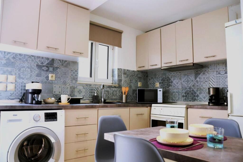 a kitchen with white cabinets and a table with a washer at Cathy's Place in Paradeísion