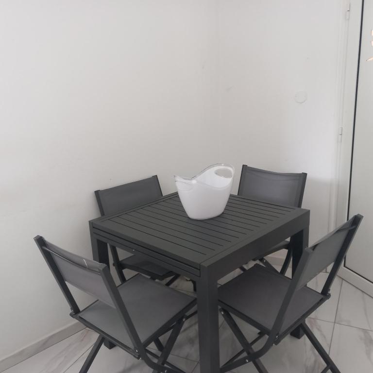 einem schwarzen Tisch mit zwei Stühlen und einer weißen Vase darauf in der Unterkunft Chez loulou in Sainte-Marie