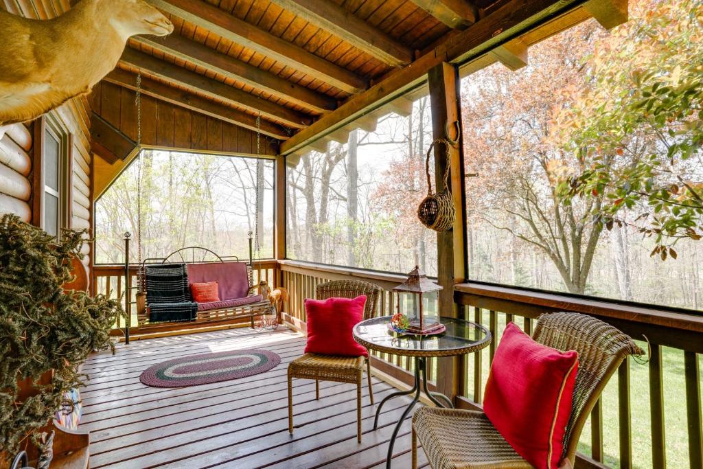 un porche cubierto con mesa y sillas en Peaceful Luray Cabin with Hot Tub, Deck and Fire Pit!, en Luray