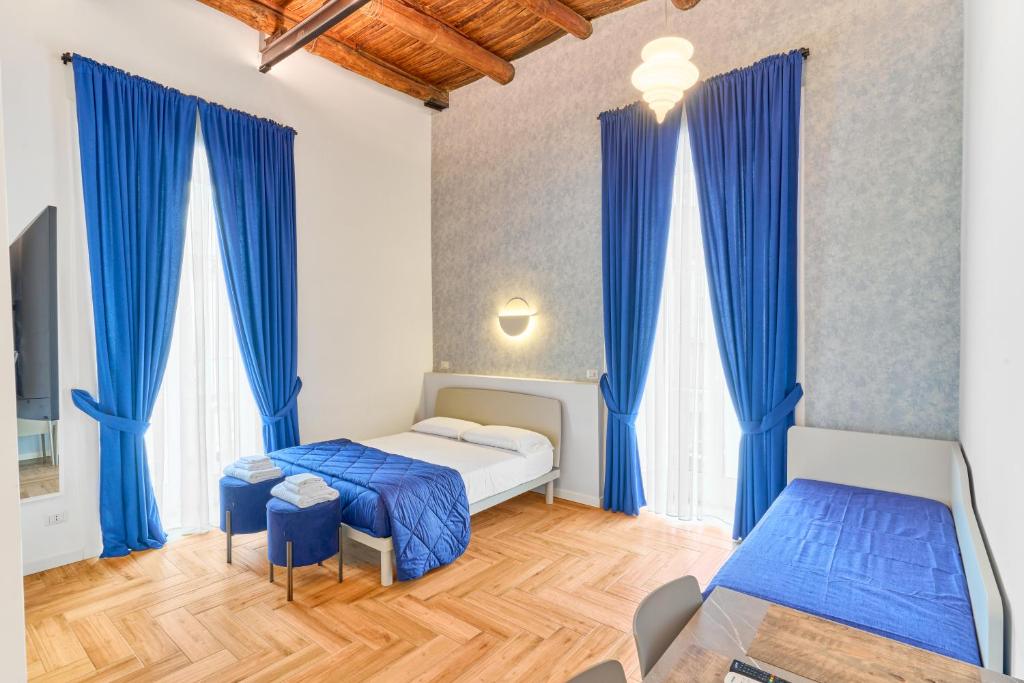 Toto e Peppino luxury rooms في نابولي: غرفة نوم بسريرين وستائر زرقاء