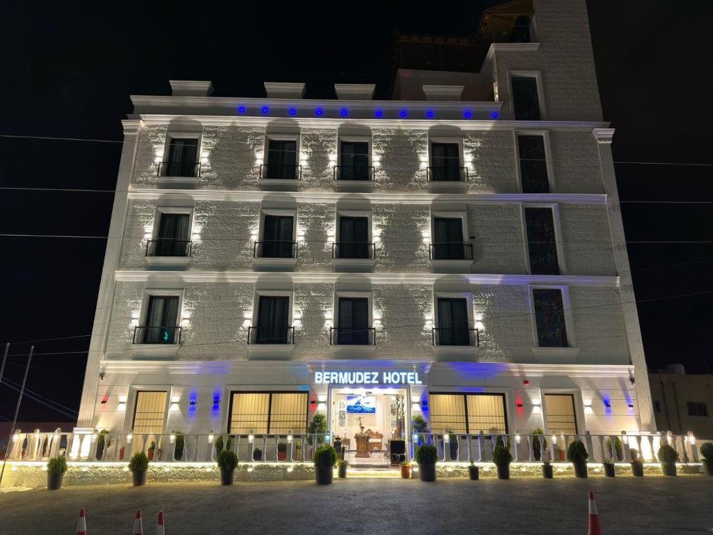Petra Bermudez Hotel في وادي موسى: مبنى ابيض عليه انوار زرقاء