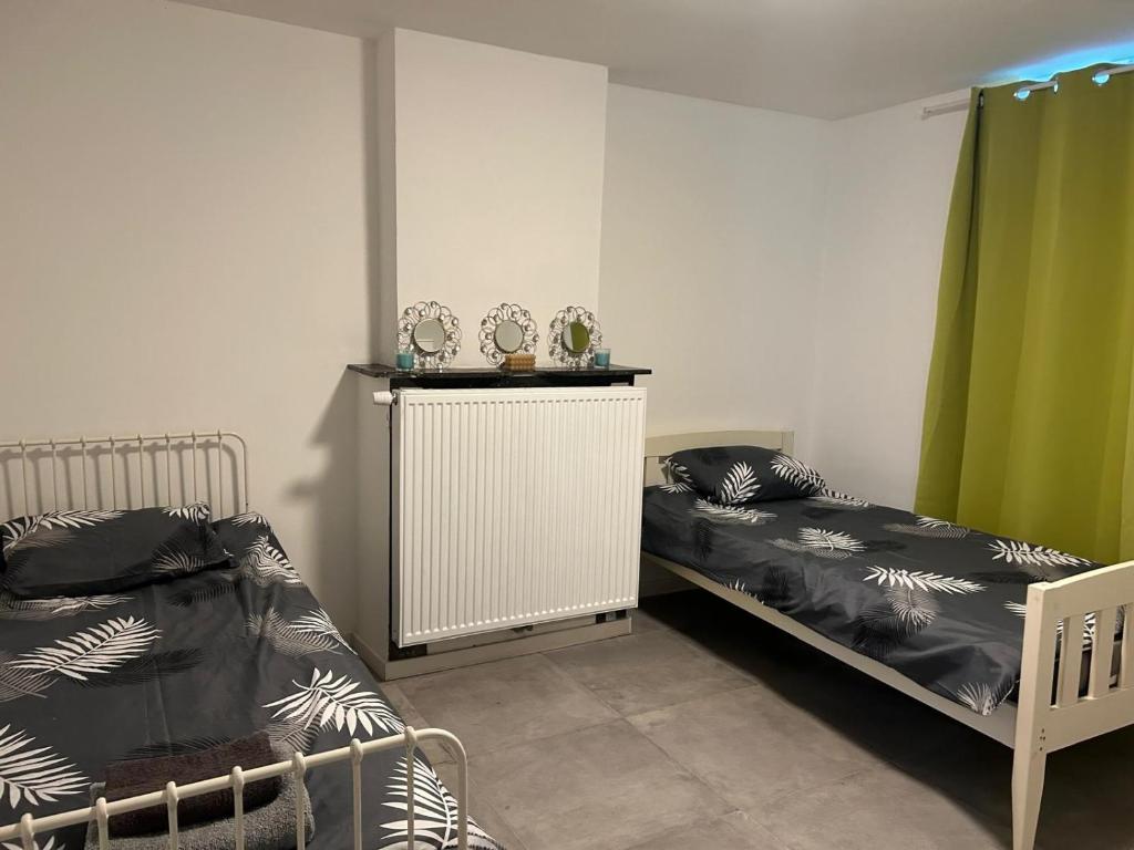 2 camas en una habitación con cortinas verdes en Chambre 2 lits simples, en Bruselas