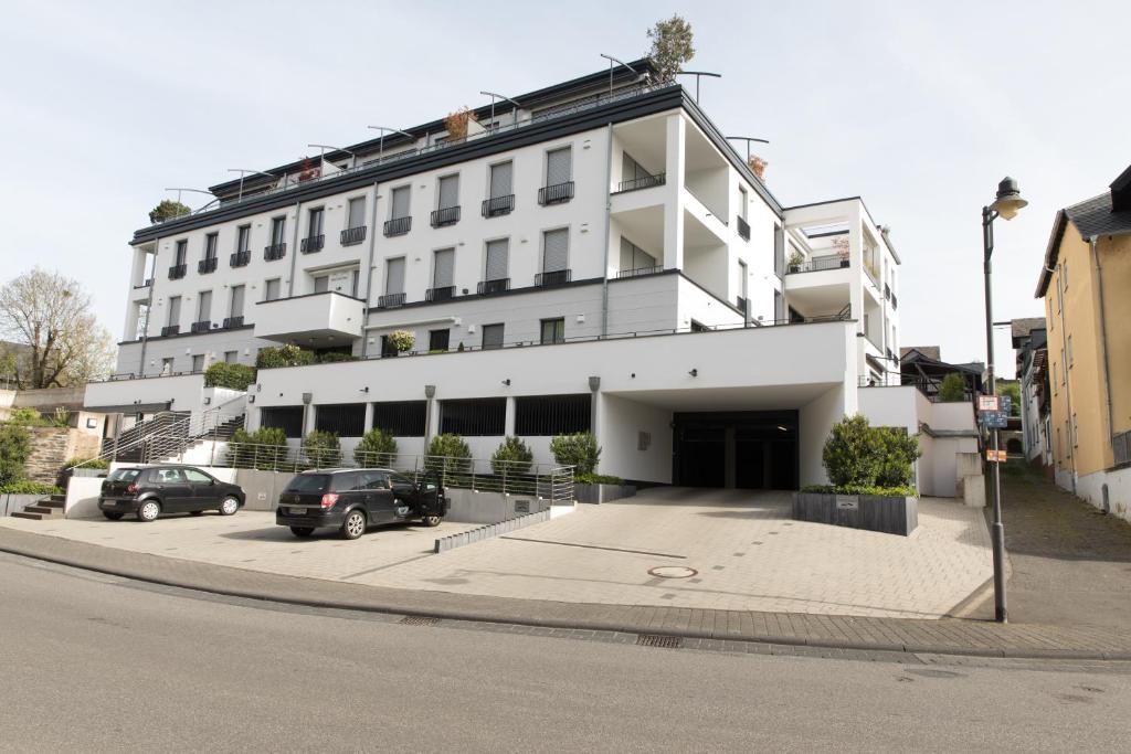 a white building with cars parked in a parking lot at NEU - MoselAUSZEIT Traben in Traben-Trarbach