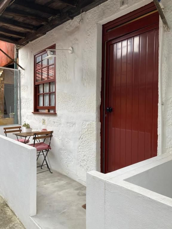 a red door on a white building with a table at J3M Houses in Porto