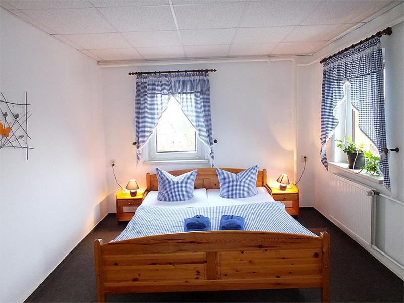 a bedroom with a large bed with two windows at Gasthaus Stiller Fritz in Bad Schandau