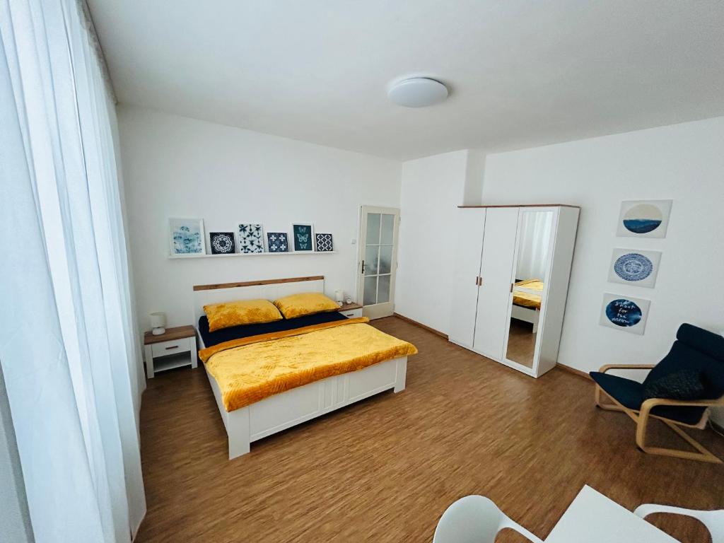 Schlafzimmer mit einem Bett mit gelber Bettwäsche und einem Spiegel in der Unterkunft Studio Apartment Bluebell in Bratislava