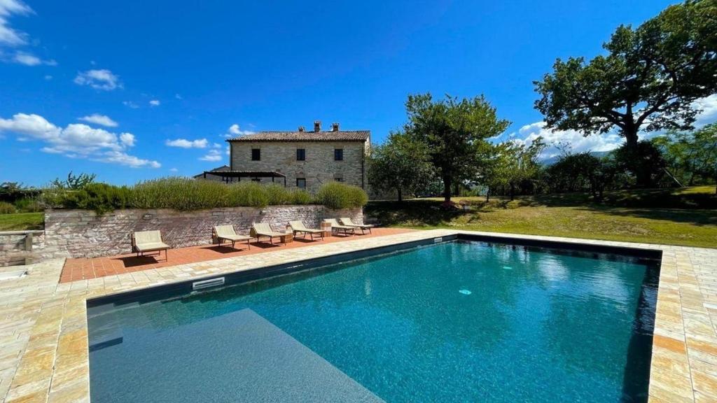 a swimming pool with a house in the background at Ferienhaus für 12 Personen in Cagli, Marken Provinz Pesaro-Urbino in Cagli